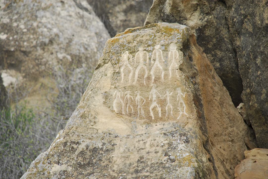 Qobustan qoruğunda əl-ələ tutub rəqs edən insanların qayaüstü təsviri